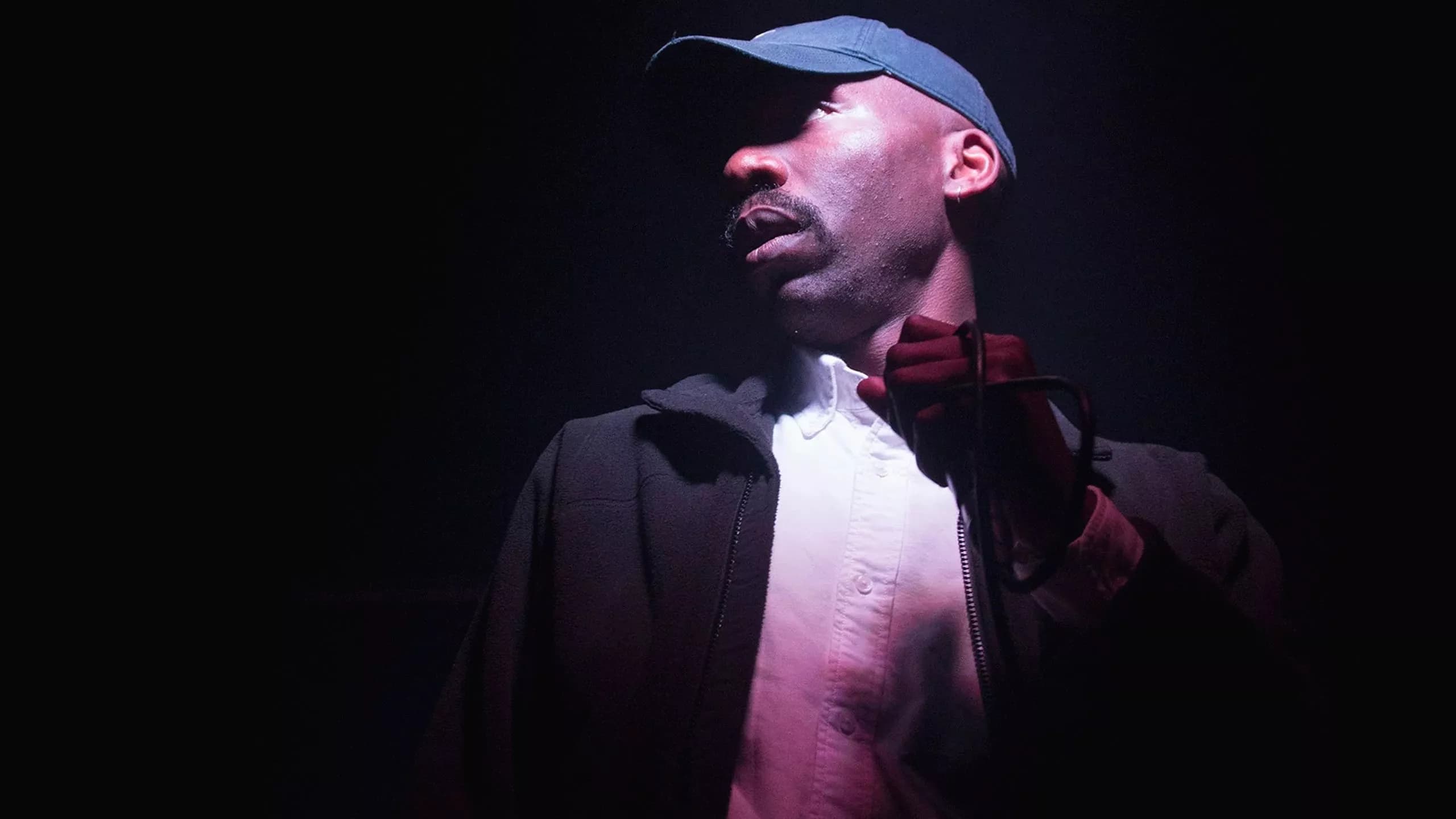Dean Blunt performing under purple stage lighting