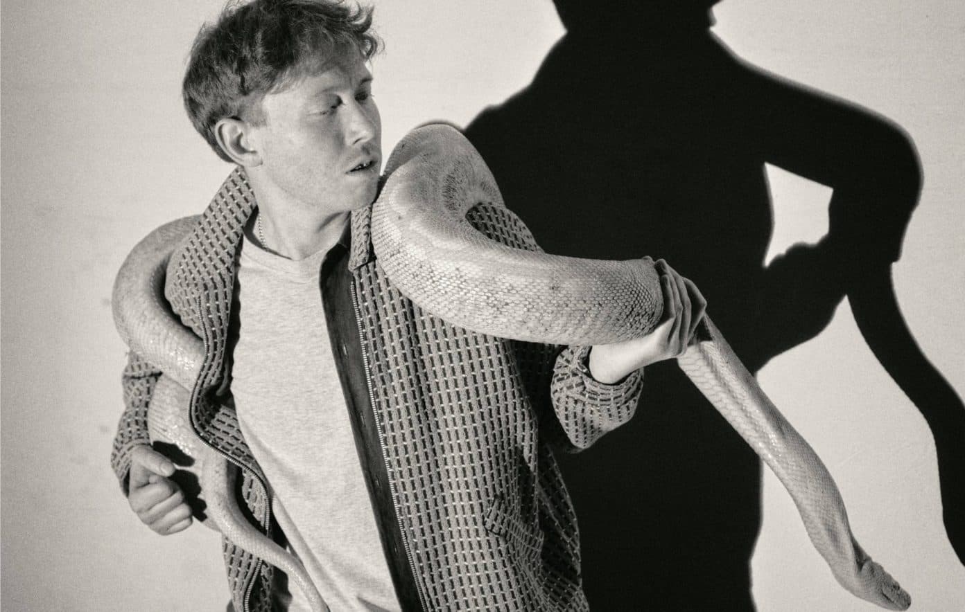 King Krule photographed in black and white with a snake over his shoulders