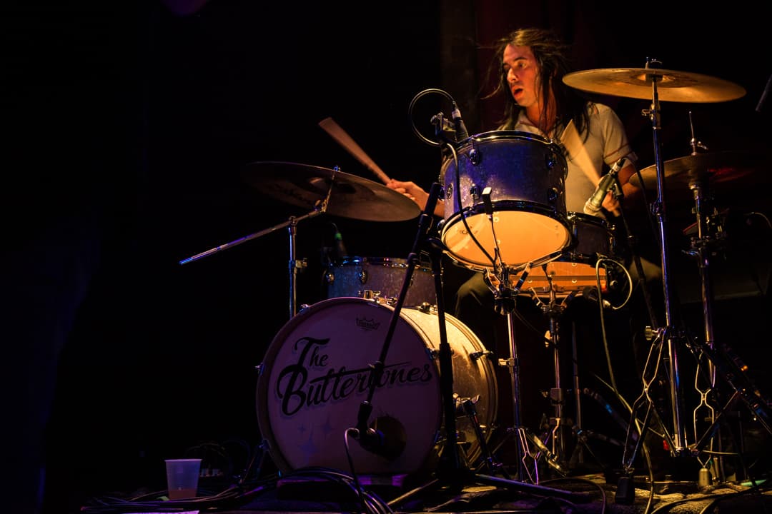 The Buttertones drummer Modeste Cobián performing behind a drum kit