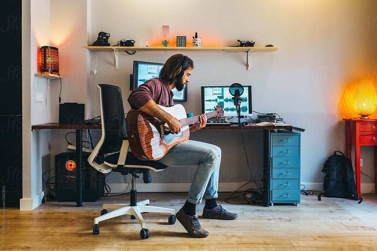 A musician recording guitar in a home production setup