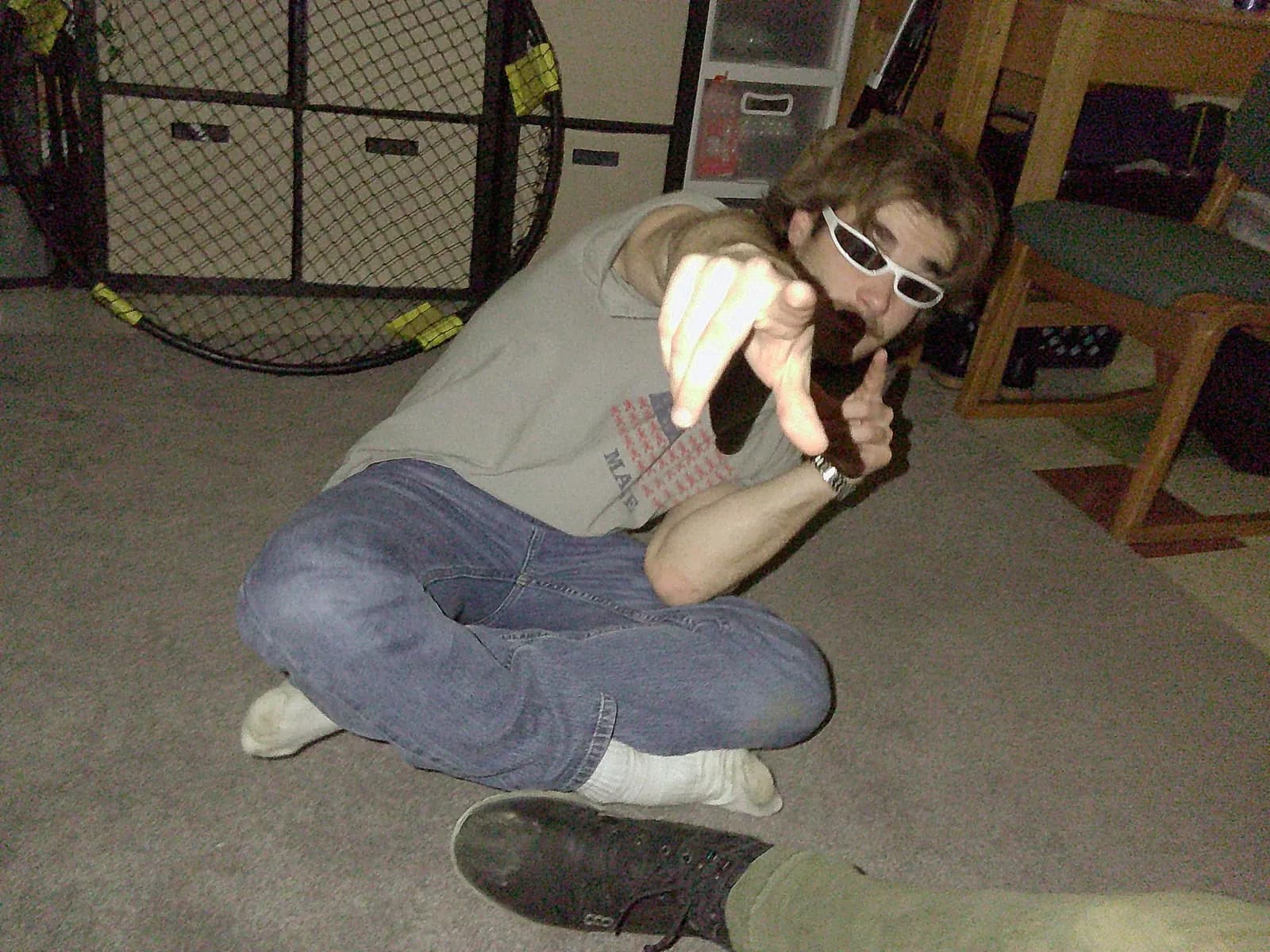 Will sitting on the floor in sunglasses and pointing toward the camera