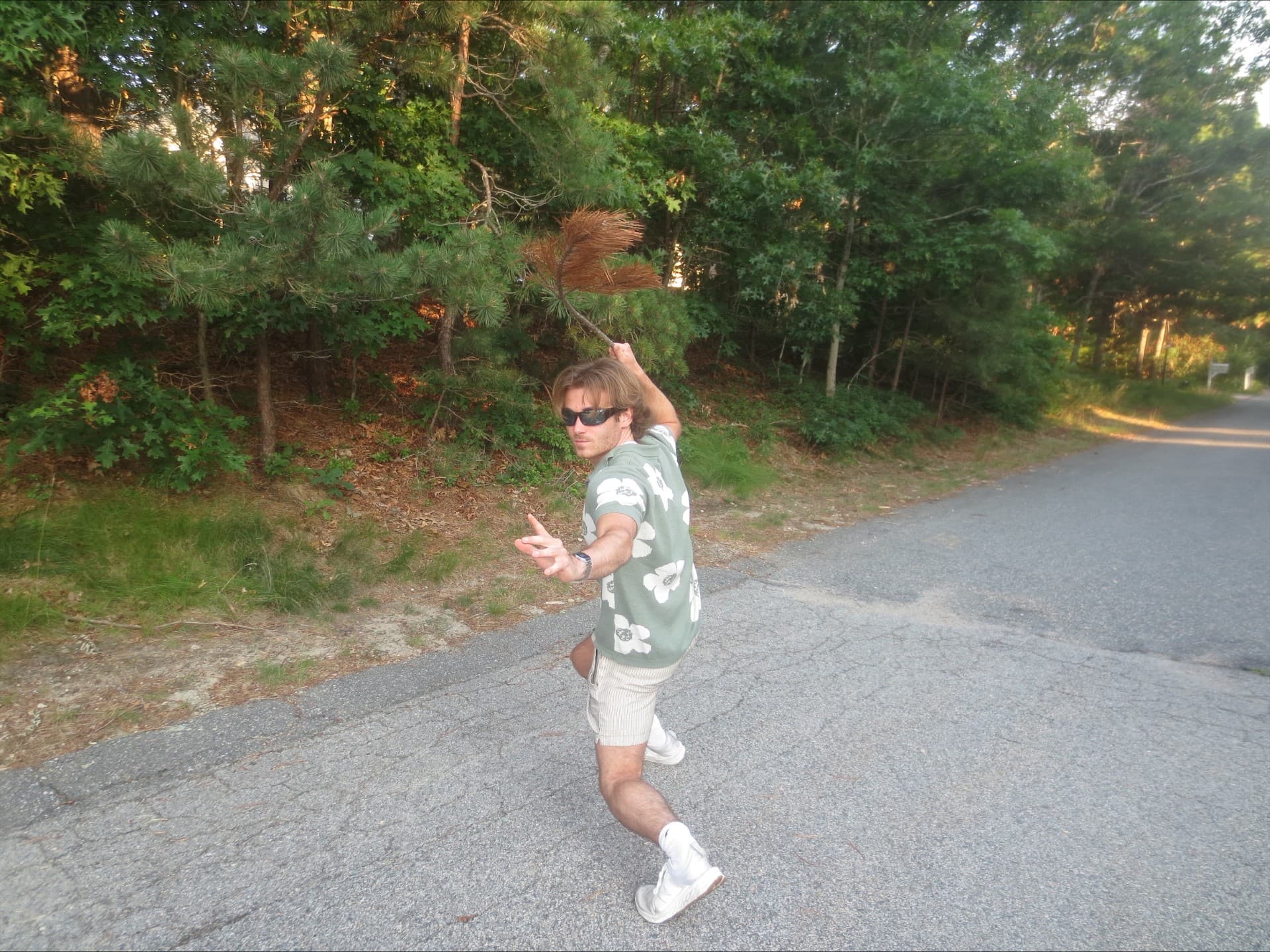 Will posing playfully on a wooded road while holding a pine branch